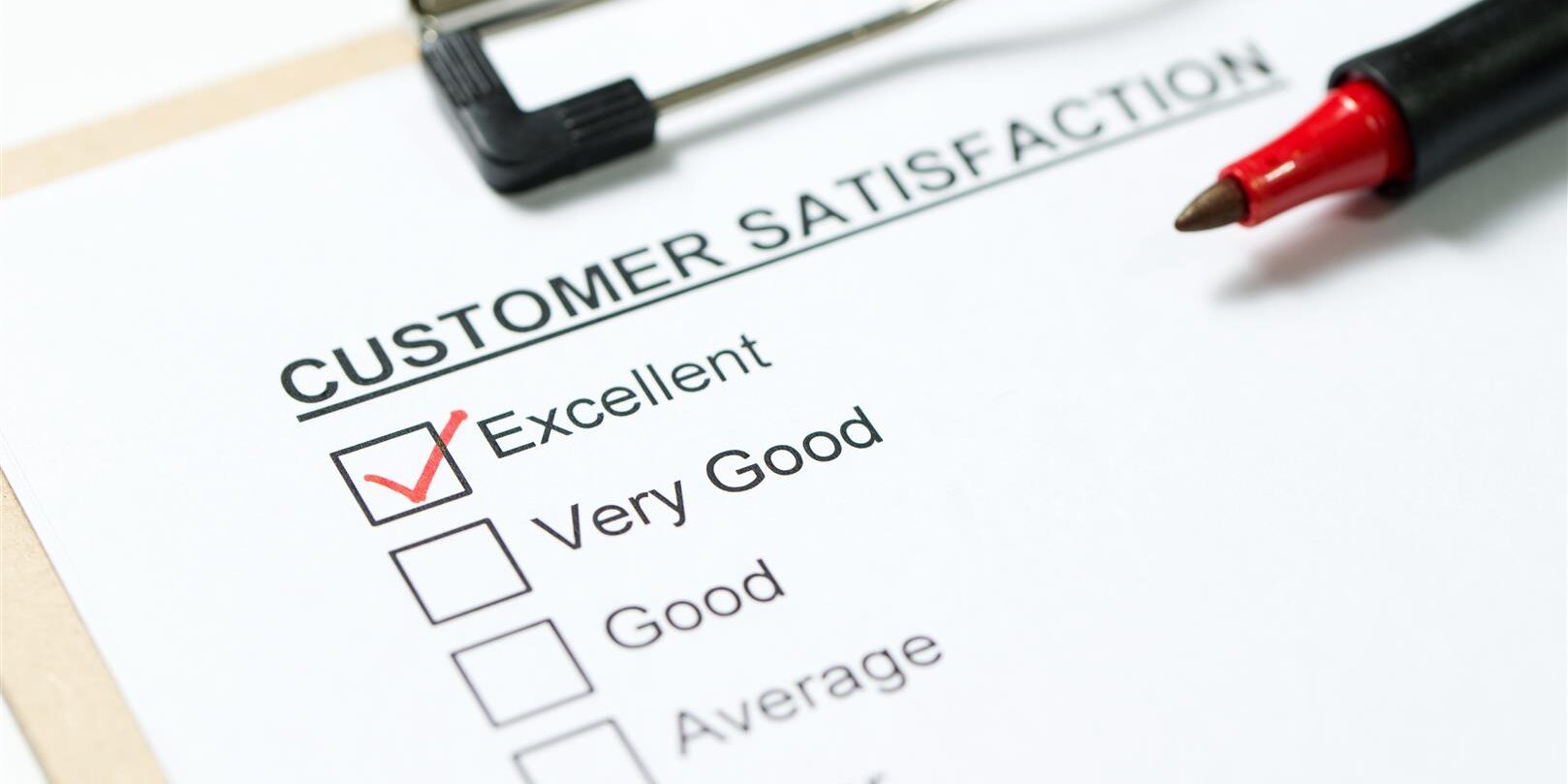 Customer satisfaction survey form on clipboard with red pen